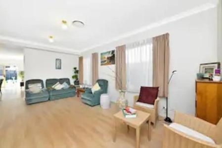a living room with two chairs and a table at Bexley North Entire 2 Storey House 4 or 5 BR 11 Beds 5 mns walk to Train Station and Close to Airport , Sydney CBD in Sydney