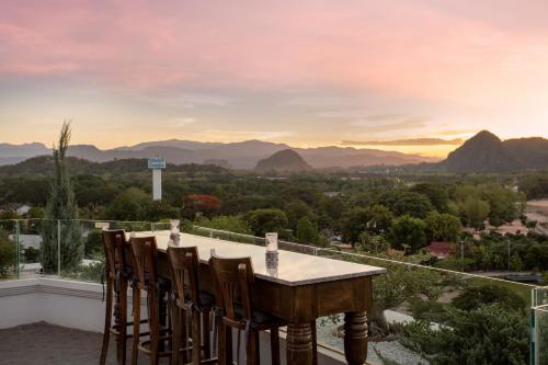 a table and chairs on a balcony with mountains at The Riverie by Katathani in Chiang Rai