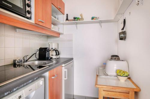 une petite cuisine avec un évier et une cuisinière dans l'établissement Vue mer - appartement pour 4, à Pornichet