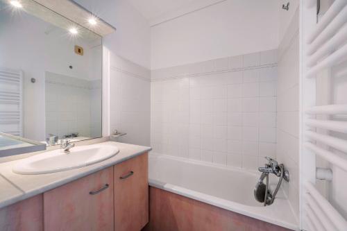 une salle de bain blanche avec un lavabo et une baignoire dans l'établissement Vue mer - appartement pour 4, à Pornichet