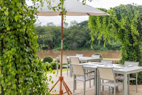 an outdoor dining area with tables and an umbrella at The Riverie by Katathani in Chiang Rai