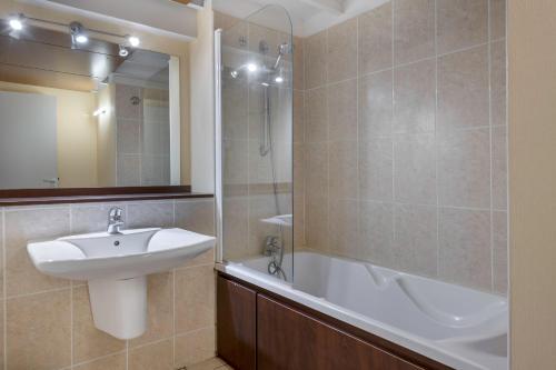 une salle de bain avec un lavabo et une baignoire dans l'établissement Duplex avec balcon, piscine et accès plage pour 4, au Croisic
