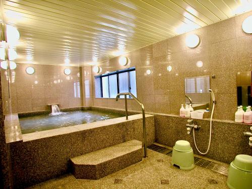 a bathroom with a large tub with a shower at Okayama Ekimae Universal Hotel in Okayama
