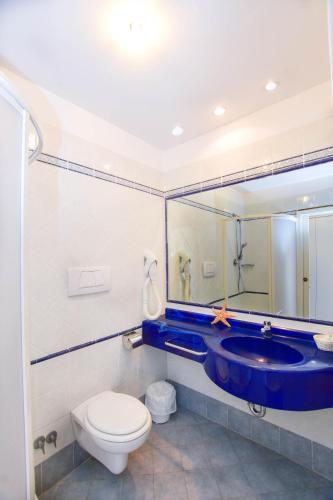 a bathroom with a blue sink and a toilet at Hotel Aqua in Cattolica
