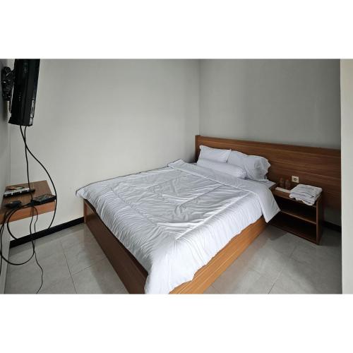a bedroom with a large bed with a wooden headboard at Guest House Saqeena Syariah Near Blitar Park RedPartner in Blitar