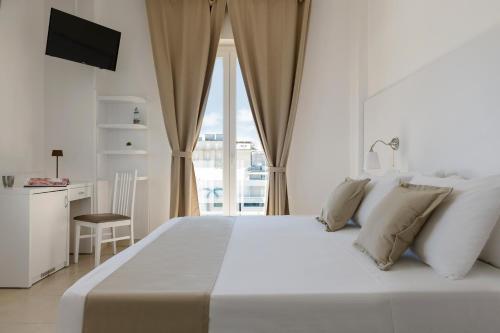 a white bedroom with a large bed and a desk at Hotel Aqua in Cattolica