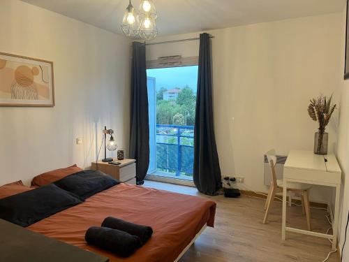une chambre avec un lit, un bureau et une fenêtre dans l'établissement Cosy Angelu, à Anglet