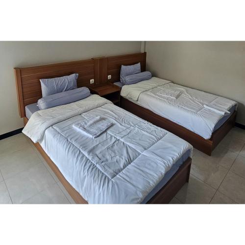 two beds sitting next to each other in a room at Guest House Saqeena Syariah Near Blitar Park RedPartner in Blitar