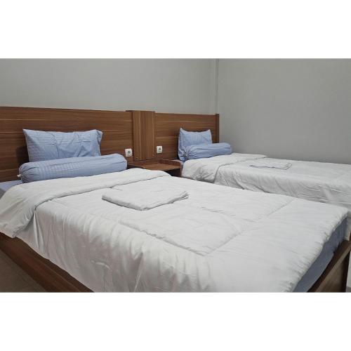 two beds in a room with white sheets at Guest House Saqeena Syariah Near Blitar Park RedPartner in Blitar