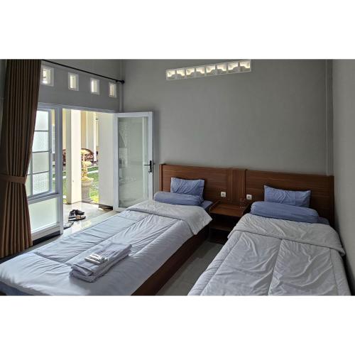 two beds sitting in a room with at Guest House Saqeena Syariah Near Blitar Park RedPartner in Blitar