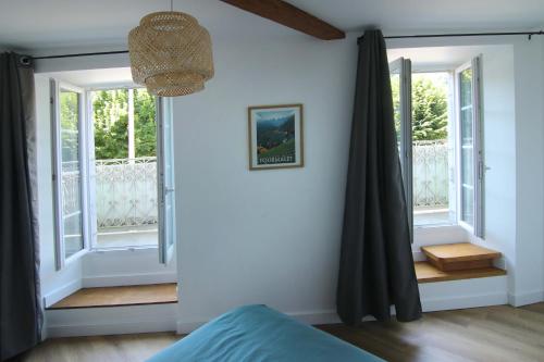 - une chambre avec des murs blancs, des fenêtres et un lit dans l'établissement Caoubère, à Bagnères-de-Bigorre