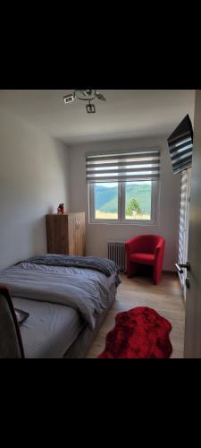 a bedroom with a bed and a red chair and a window at Apartman Zlatar-Vasiljevic in Nova Varoš