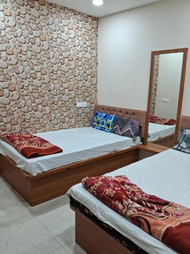 two beds in a room with a stone wall at Hotel Ruby in Ujjain