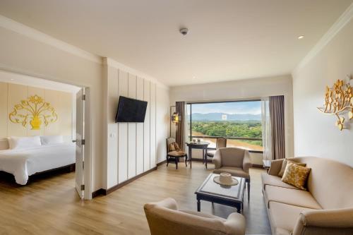 a hotel room with a bed and a living room at The Riverie by Katathani in Chiang Rai