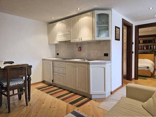 a kitchen with white cabinets and a table and a bed at La Bombetta Gialla di Elisa e Marco in Morgex