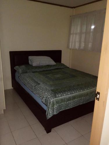 a bedroom with a bed with a green comforter at Mactan Cebu House in Cebu City