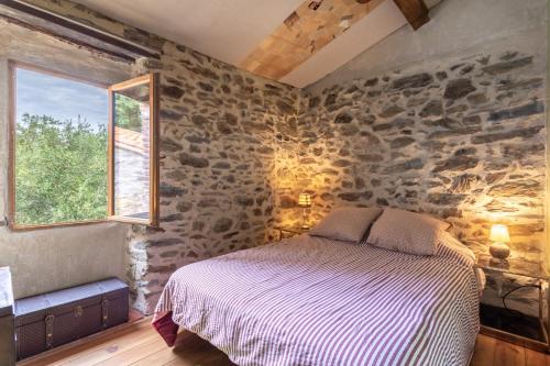 a bedroom with a bed in a room with stone walls at Mas Vizern avec bain nordique in Taillet