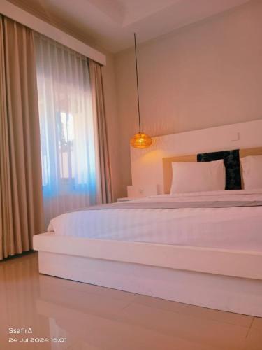 a bedroom with a large white bed and a window at Living Trawangan Hotel in Gili Trawangan