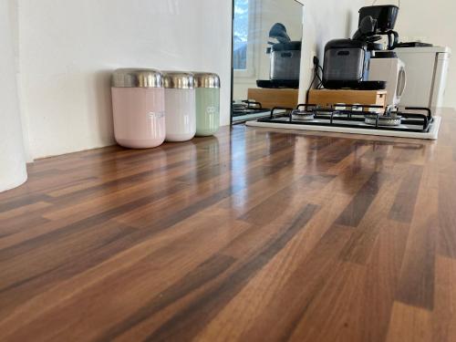 une cuisine avec un plancher en bois et trois poubelles dans l'établissement Gîte de la chapelle, à Landrethun-lès-Ardres