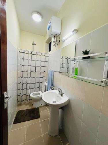 a bathroom with a white sink and a toilet at Logic Stays 2 Bedroom Arusha City Centre in Arusha