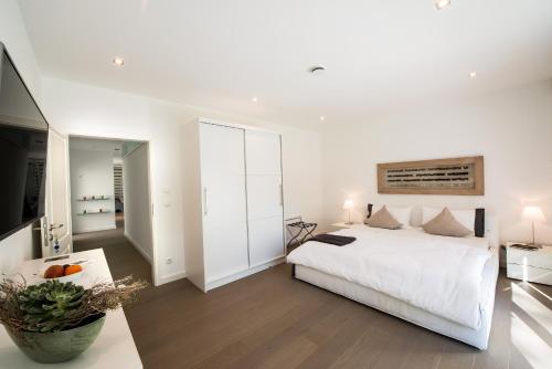 a white bedroom with a bed and a mirror at View & Garden Villa Schauenstein in Schauenstein