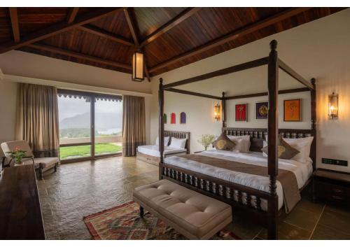 a bedroom with a large bed and a large window at Malhar Machi Mountain Resorts in Mulshi