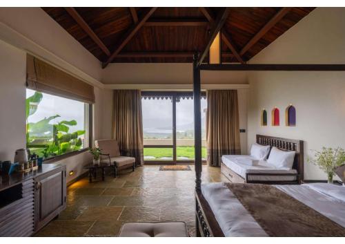 a bedroom with a bed and a couch and a window at Malhar Machi Mountain Resorts in Mulshi