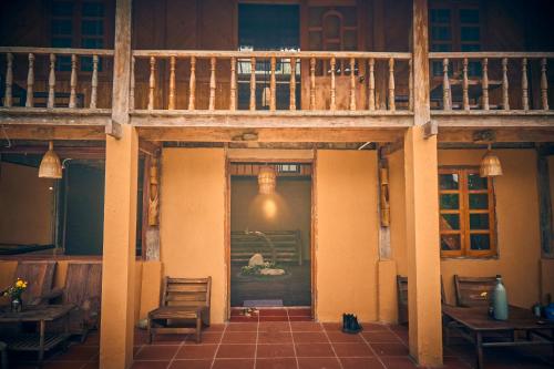 a building with a balcony and aoyer with tables and chairs at Sa Moc - La Maison House & Bungalow in Sa Pa