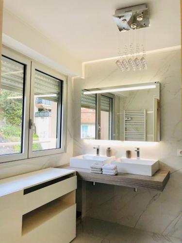 une salle de bain avec deux lavabos et un grand miroir dans l'établissement Appartement Cosy, à Menton