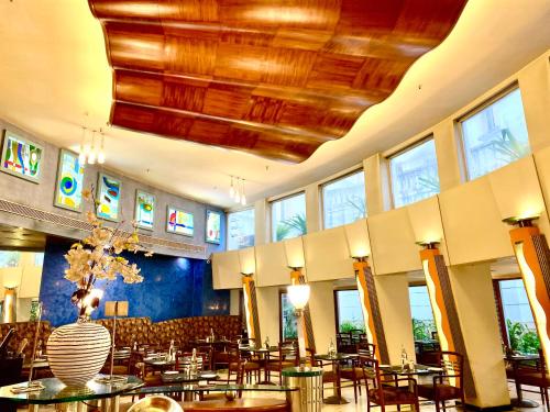 a restaurant with tables and chairs and a vase at The Manohar Hyderabad in Hyderabad