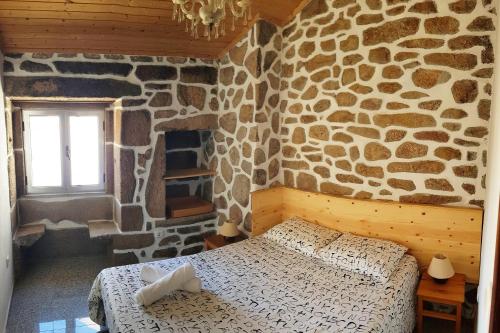 a bedroom with a stone wall with a bed and a window at Casa da Padeira in Trancoso