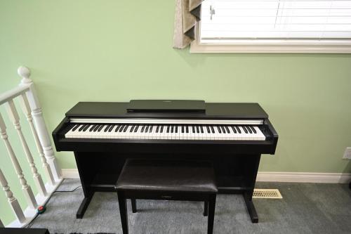 a black piano in a room with a window at 48a Luxury Lake Home W Massage Meditation Gym Ac in Calgary