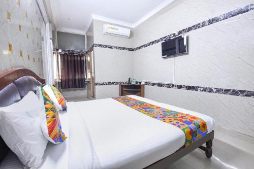 a bedroom with a bed and a tv on the wall at FabExpress Le Royal Inn in Chennai