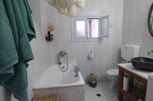 a bathroom with a tub and a toilet and a sink at Chrisi's and Jasmin's house in Patmos