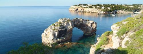 an island in the water with an arch in it at Hotel Pinos Playa in Cala Santanyi