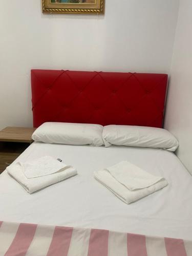 a bed with a red headboard and two white towels at Hostal Granvia 628 in Barcelona