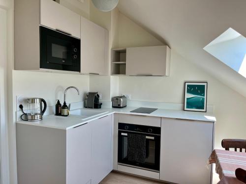 une cuisine avec des armoires blanches et un four noir dans l'établissement Studio au coeur de la vieille ville, à Annecy