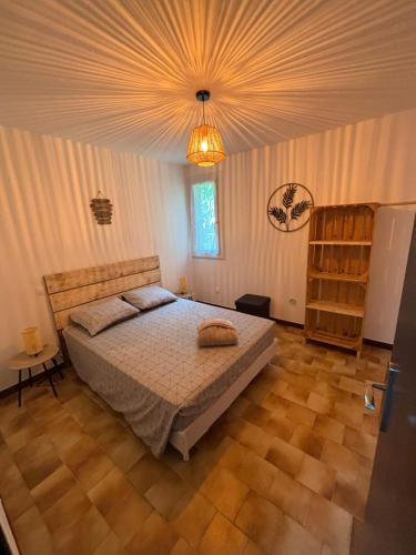 une chambre avec un grand lit et un lustre dans l'établissement L'atelier cosy!, à Laroque