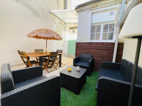 a patio with chairs and a table and an umbrella at Les Remparts, 5min du ZooParc in Saint-Aignan