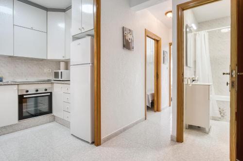 Una cocina con electrodomésticos blancos y un refrigerador blanco. en Sunflower Tailandia_Santa Pola, en Santa Pola