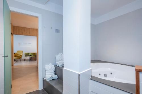 a white bathroom with a tub and a dining room at ARTIEM Audax - Adults Only in Cala Galdana