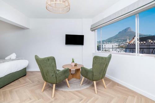 a bedroom with a bed and two chairs and a table at Flamingo on Hope in Cape Town