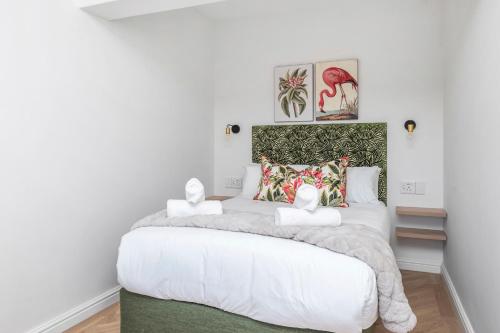 a bedroom with a large white bed with two white towels at Flamingo on Hope in Cape Town