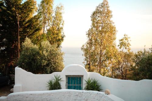 a white house with a blue door and trees at Casablanca Rooms Dhërmi in Dhërmi