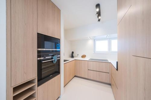 a kitchen with wooden cabinets and a television at Amandine - Luxury 3 bedrooms apartment with free parking in Ostend
