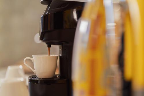 a coffee maker pouring coffee into a coffee cup at Ortigia Sitari suites in Siracusa