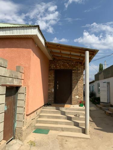 a brick building with a black door and stairs at Gulnara guesthouse in Kochkorka