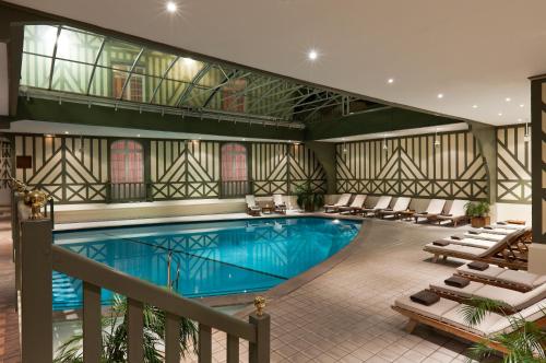 ein Pool in einem Hotel mit Liegestühlen um ihn herum in der Unterkunft Hôtel Barrière Le Normandy in Deauville