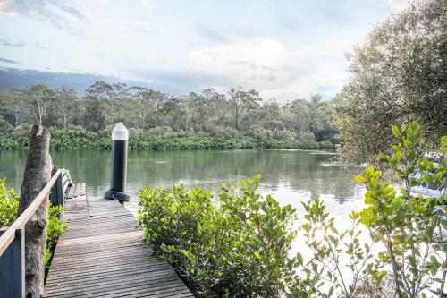 a wooden boardwalk leading to a river with trees at East Hills Waterfront Bliss in East Hills
