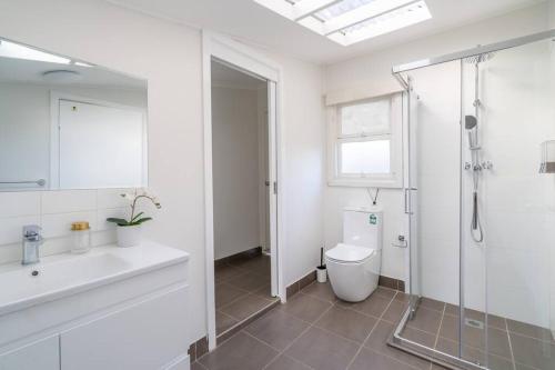 a bathroom with a shower and a toilet and a sink at East Hills Waterfront Bliss in East Hills